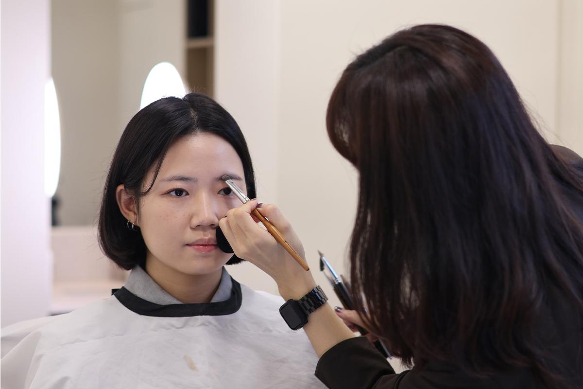 化妝師正在進行眼部化妝,引導色彩顏料塗抹,呈現專業的化妝技術。