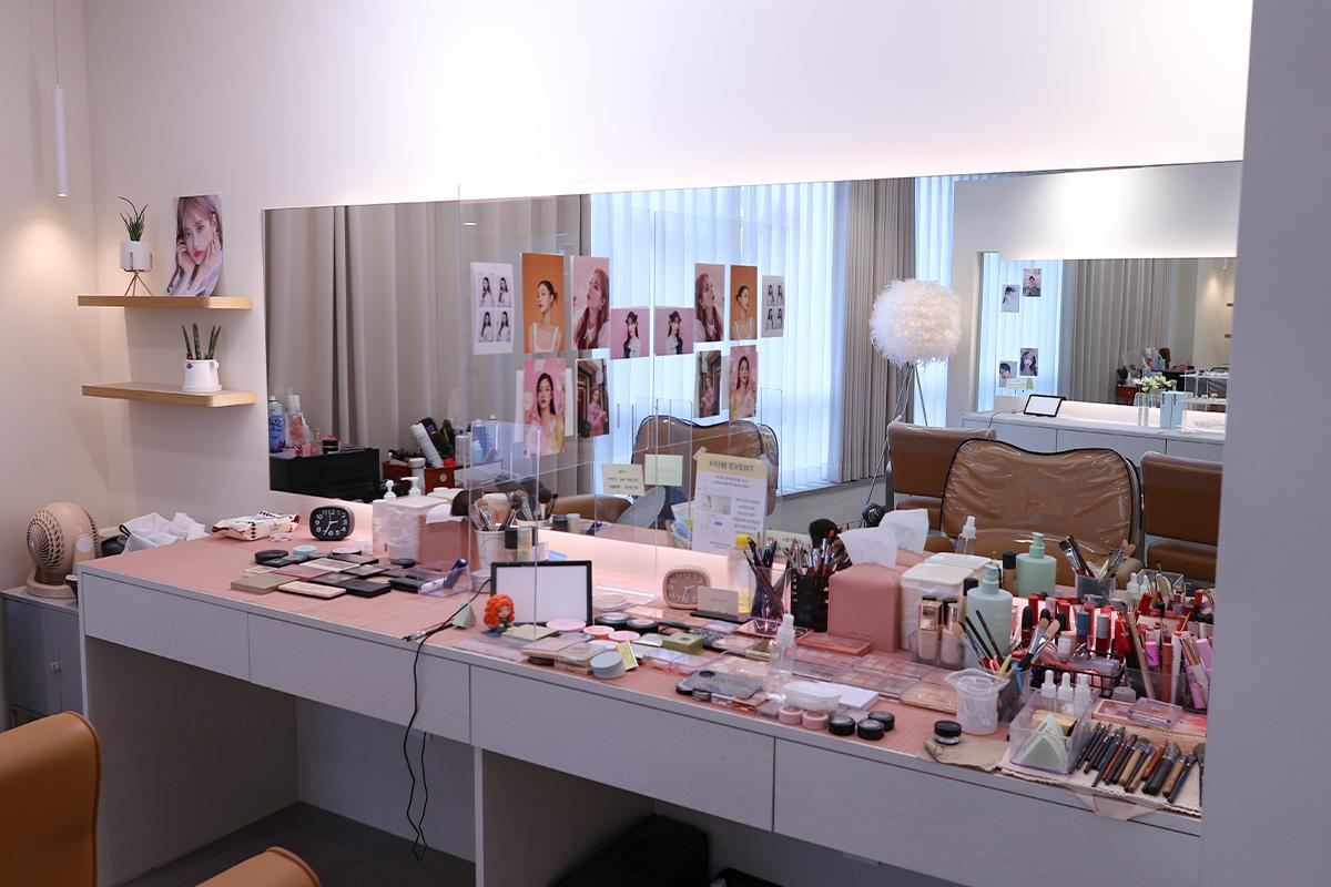 美容院內的化妝臺擺滿了各種化妝品,顯示其專業性,背景展示了美容相關的照片和資訊。