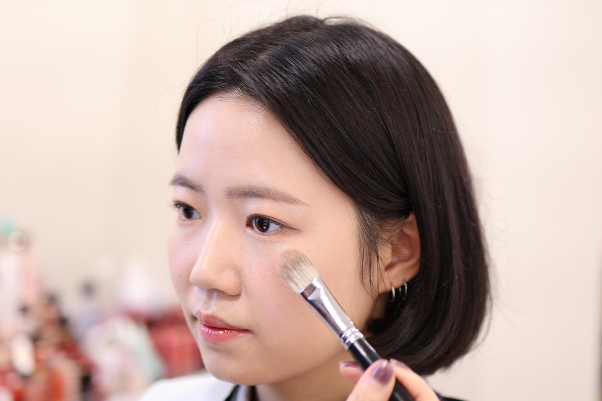 修容過程展示,化妝師正在精緻地進行下巴線條造型,增強妝容的立體感。