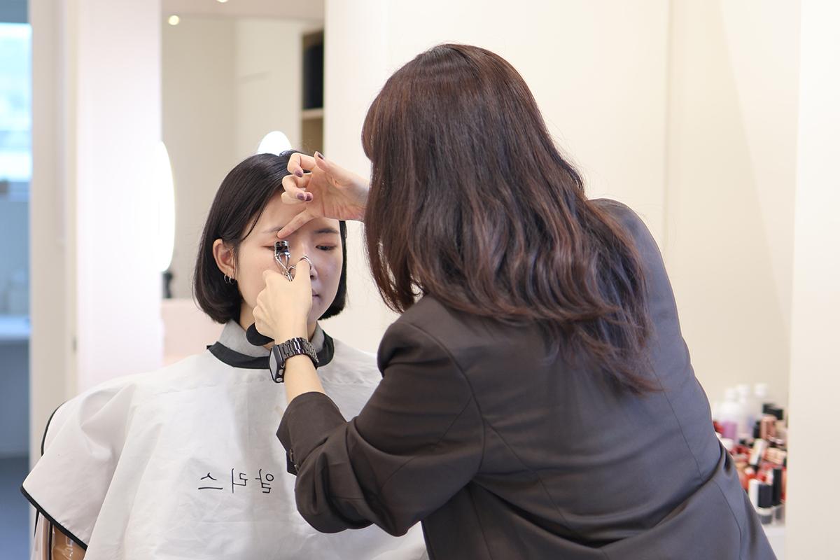 化妝師正在進行眼部化妝,展示了精確眼線的描繪技巧。