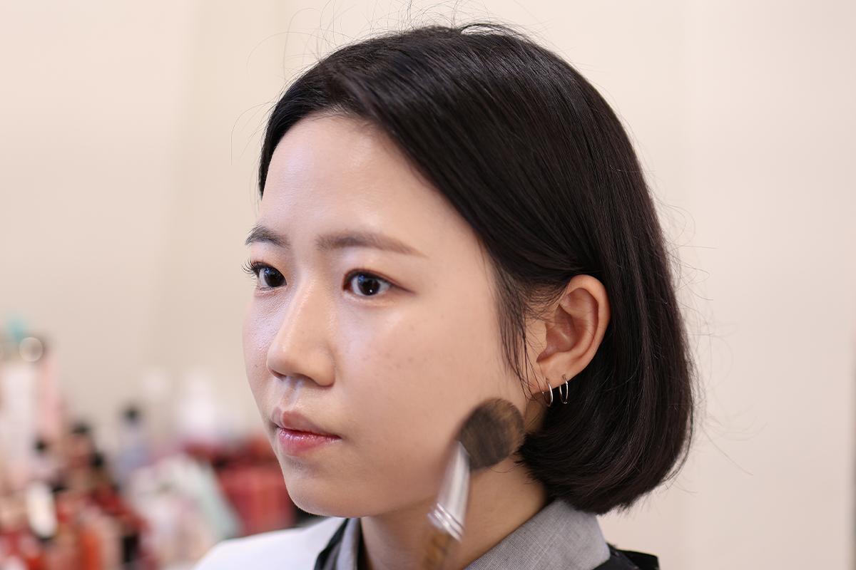 化妝師正在進行鼻影修飾,展示了修容技巧,使下巴線條更顯利落。