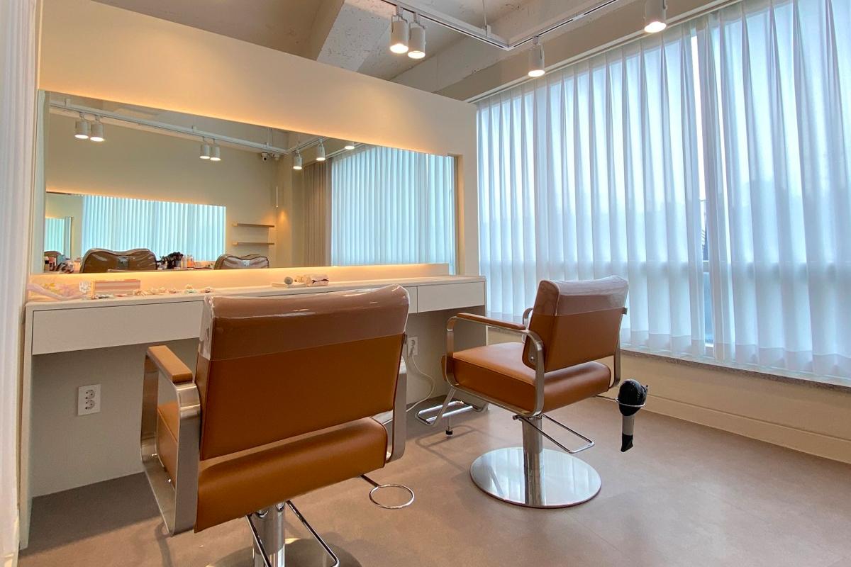 化妝服務區,兩張褐色化妝椅和大窗戶,室內明亮寬敞,提供舒適的妝容體驗。