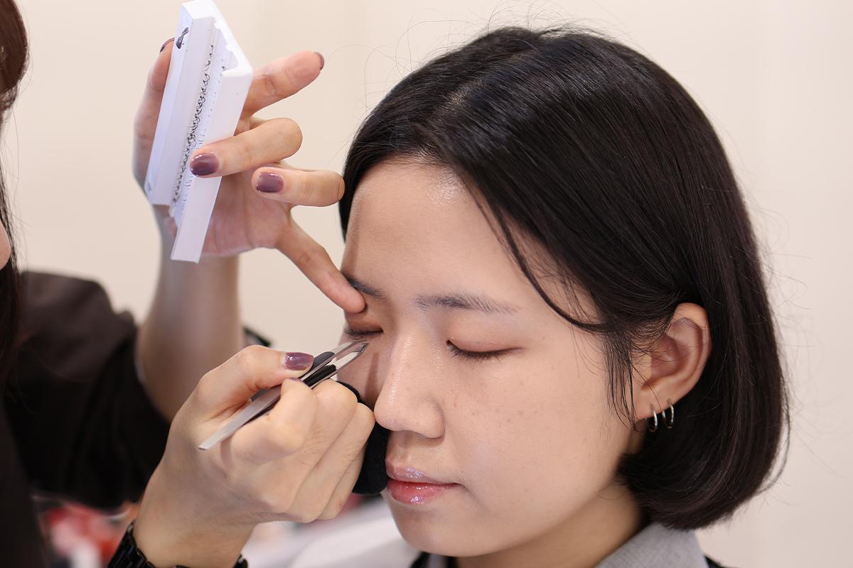 化妝師正在進行細膩的眼部化妝工作,展示了眼部化妝的專業技術。