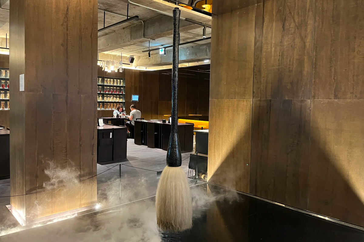 桥村笔房内中央展示着神秘的大型毛笔，周围弥漫着雾气，增添了奇幻的氛围。