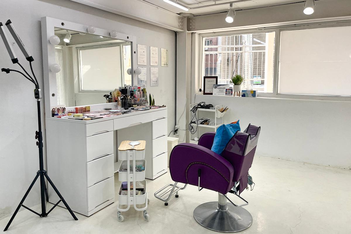Inside Roa Makeup, displaying a white-themed makeup studio with a styling chair and mirror.
