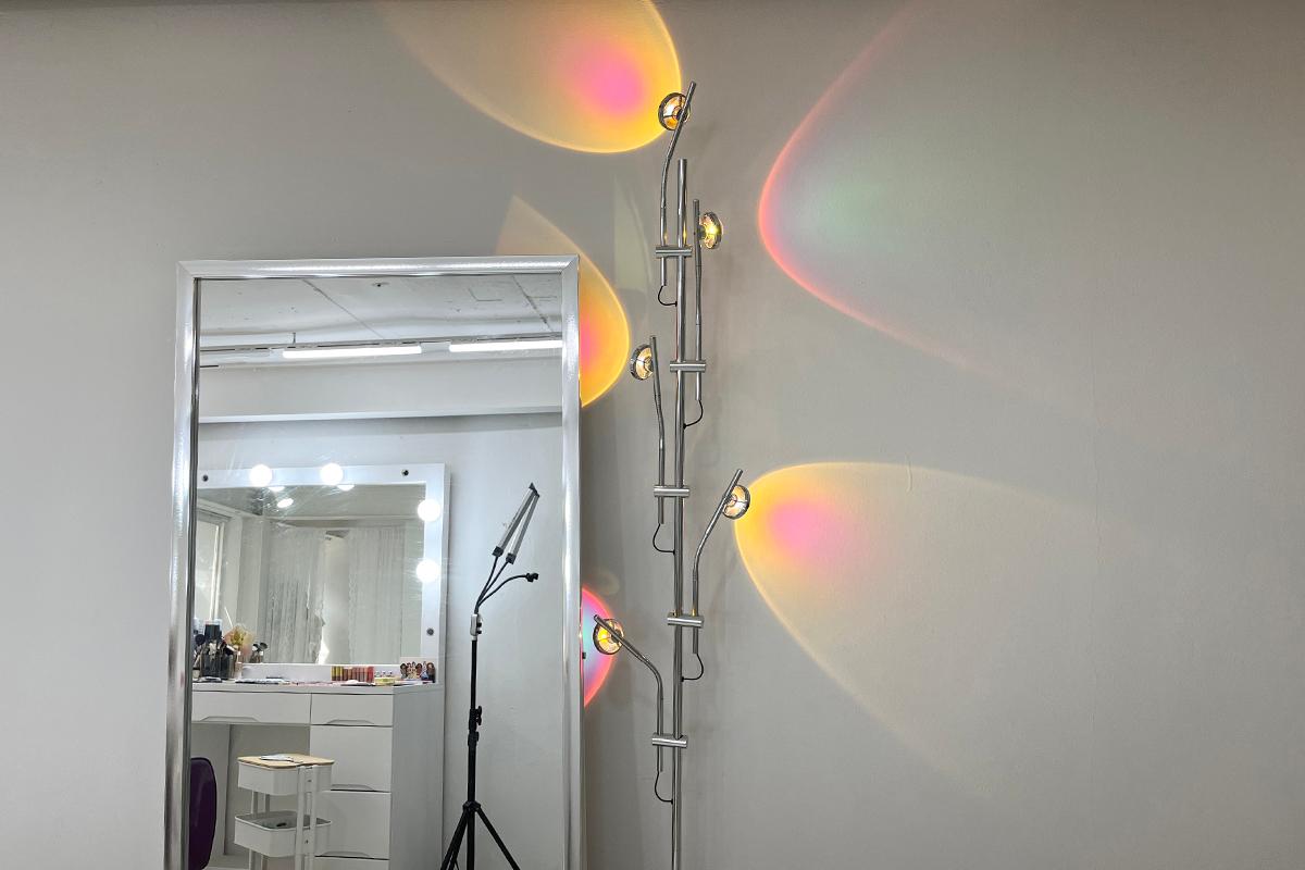 A decorative light fixture in Roa Makeup, casting colorful hues on the interior wall.