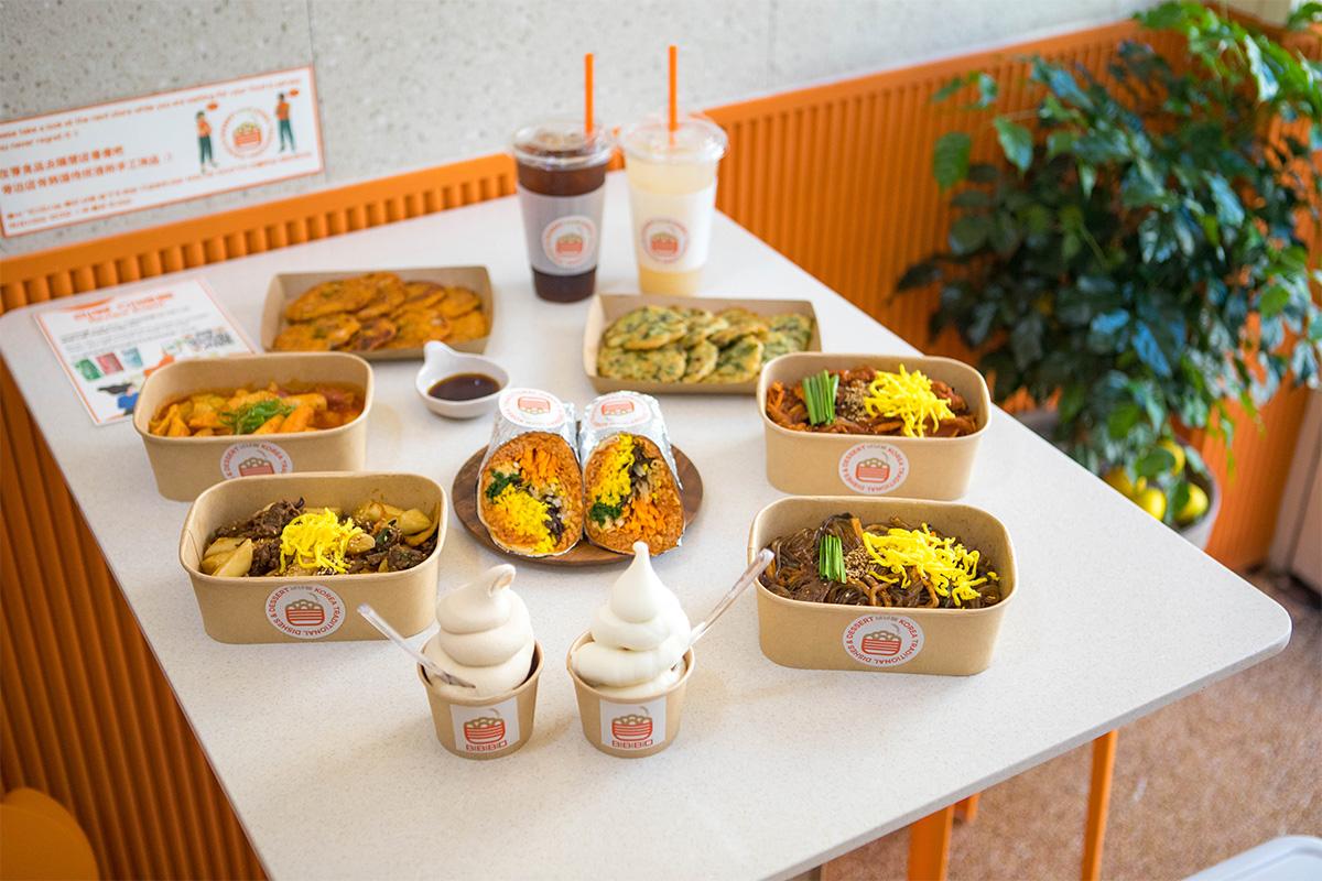 A variety of Korean dishes served in eco-friendly packaging at BIBIBIM restaurant near Gamcheon Culture Village, ideal for casual dining with options like burritos and ice creams.