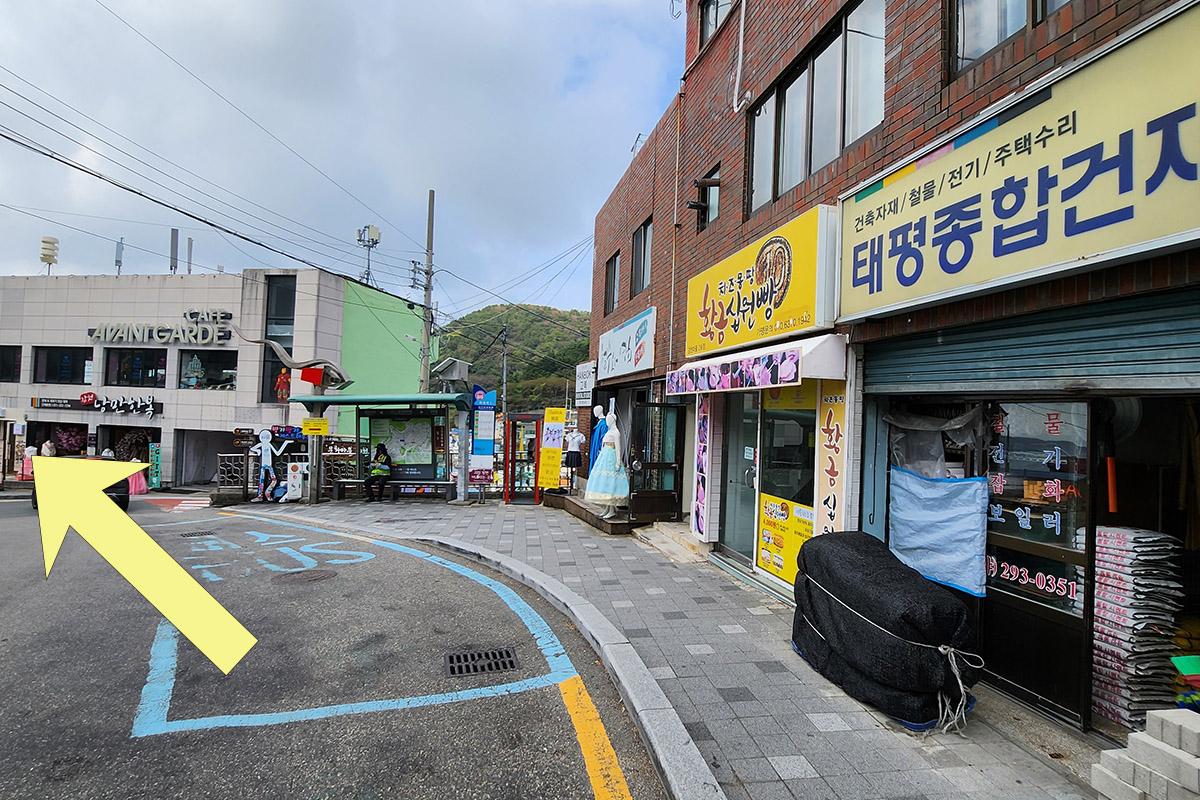 Street view leading to Gamcheon Culture Village, with indications to turn left to find BIBIBIM cafe for a tasty Korean meal.