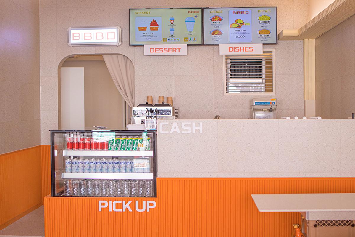 Interior view of BIBIBIM cafe's ordering counter, featuring a serene and modern design with menu screens displaying desserts and Korean dishes inside Gamcheon Culture Village.