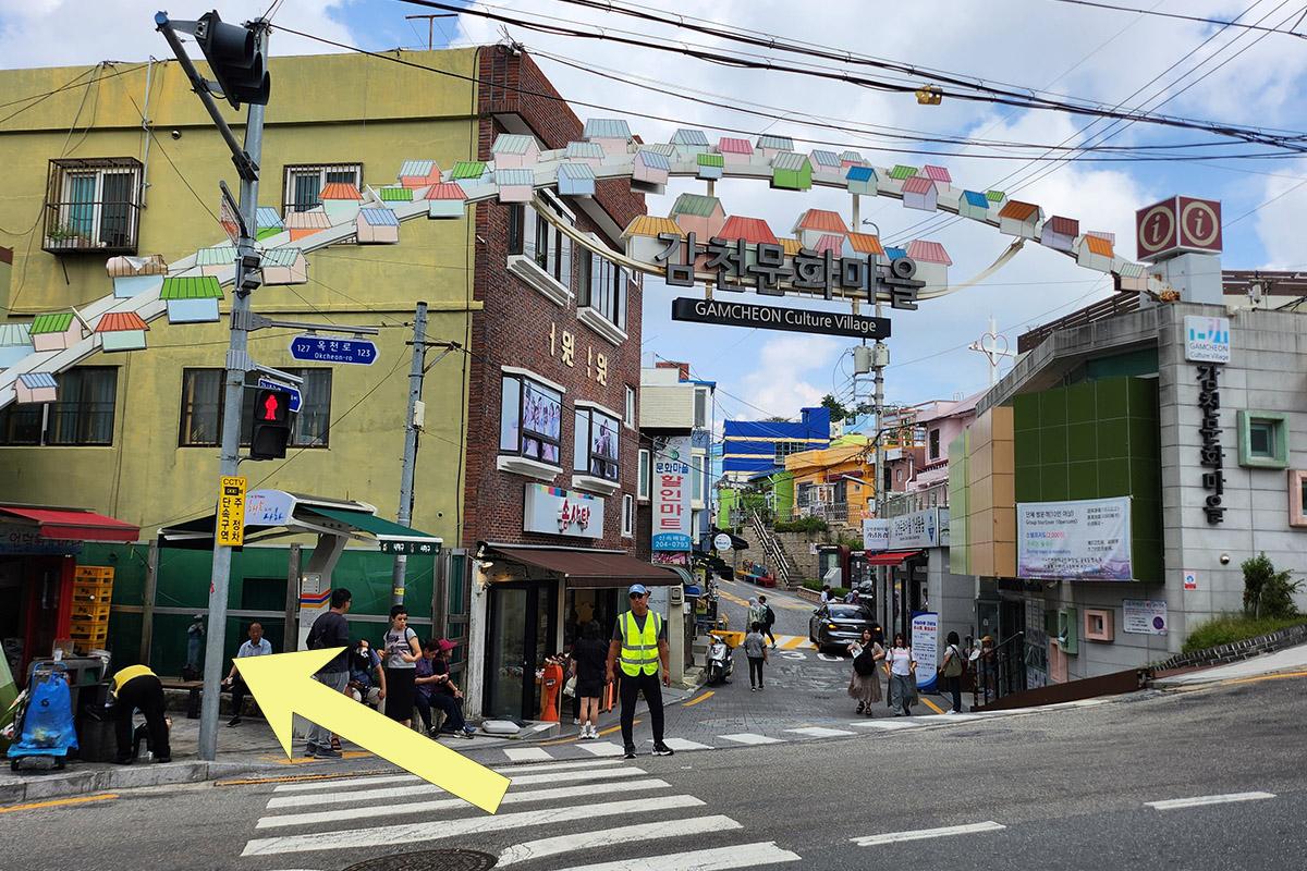 Intersection near Gamcheon Culture Village with directional signs pointing left, guiding visitors towards BIBIBIM restaurant.