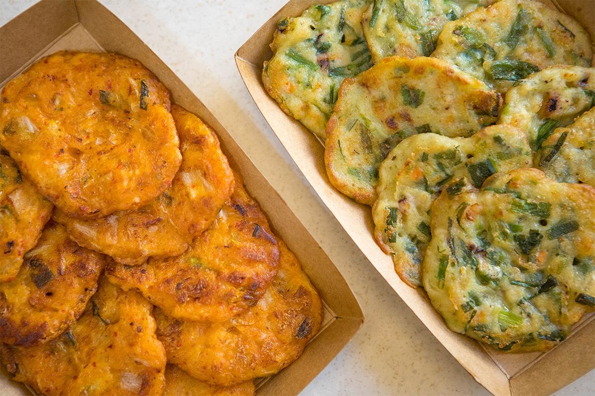 Korean pancakes, including kimchi and seafood flavors, neatly presented in eco-friendly trays at BIBIBIM cafe, a must-try for visitors.