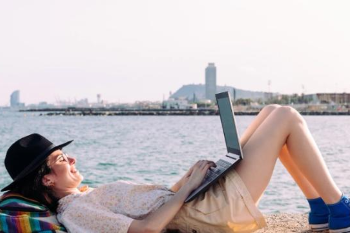 數碼遊牧生活：女子坐在海旁使用筆記型電腦，享受工作與度假結合的自由自在生活方式
