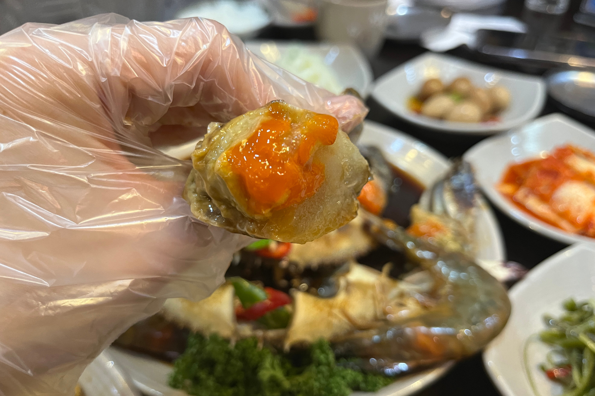 Close-up of raw marinated crab showcasing bright orange eggs at Hamcho Ganjang Gejang, Myeongdong, Seoul.