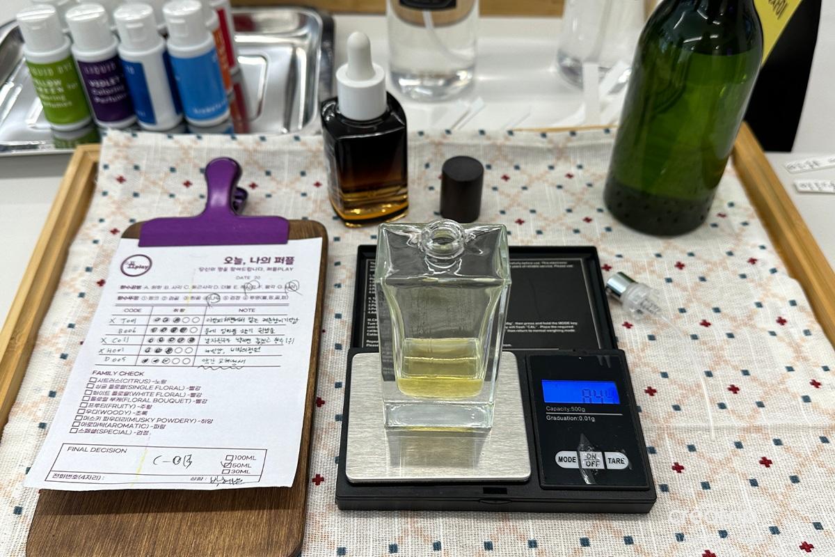 Sealing a perfume bottle at Perfume Play Gangnam using machinery to ensure a secure closure.