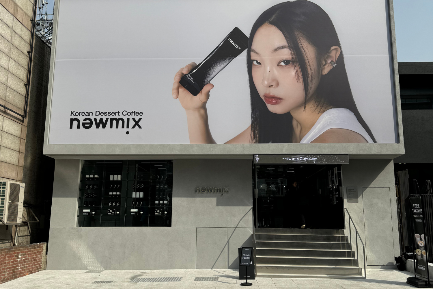 韓国のソウルに位置するニューミックスコーヒーの北村店外観。大きな看板には、ニューミックスコーヒーのスティックを持った人物が描かれている。