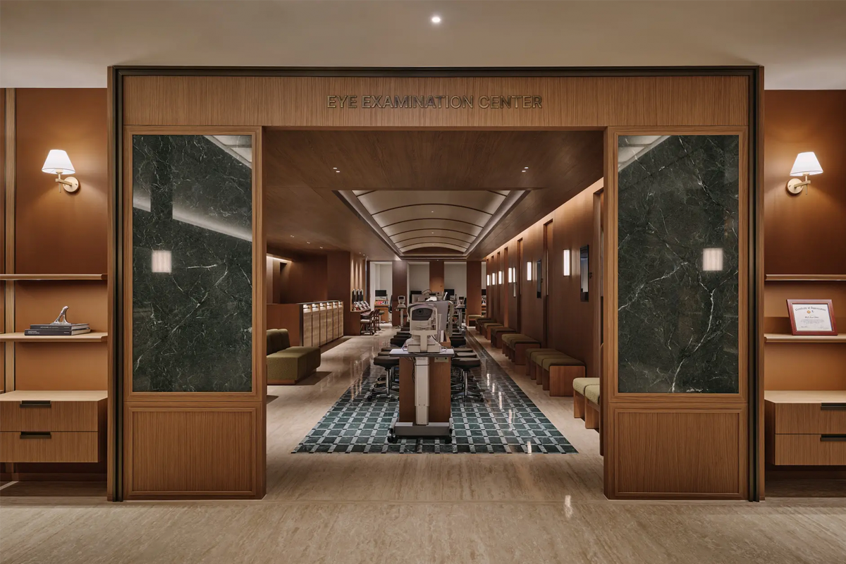 高雅木質與大理石裝潢的眼科檢查中心入口，內部排列視力檢測儀器與候診座椅，適合介紹首爾醫美、眼科或6月就醫旅遊資訊。