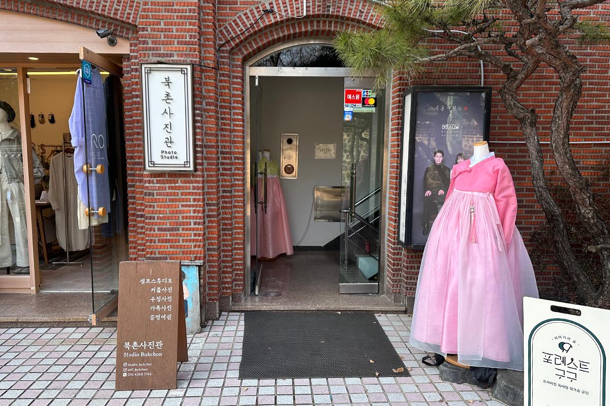 Entrance to Bukchon Photo Studio displaying traditional hanbok on a mannequin.