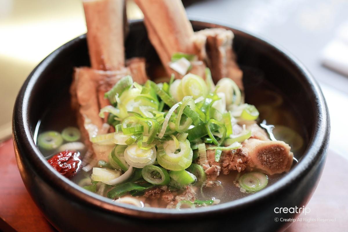 韓國牛排骨湯，放在黑色石鍋中，上面有滿滿的蔥花