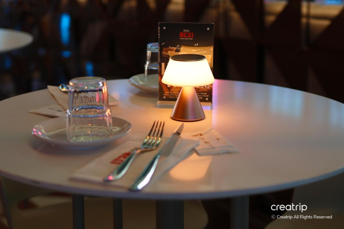 bistro MEXI的用餐桌，灯光柔和，餐具整齐为您提供舒适的用餐环境。