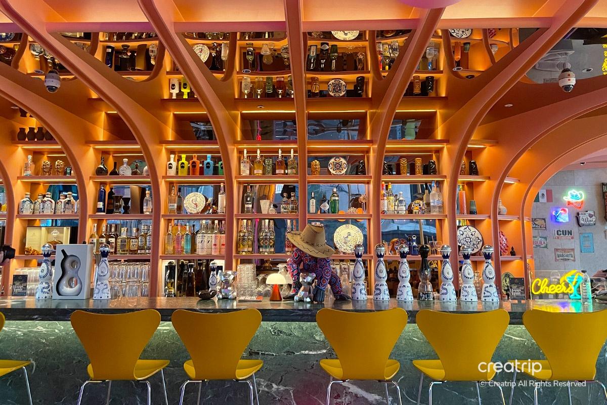 bistro MEXI的酒吧，全景展示美丽的瓶子装饰，提供丰富的饮料选择。