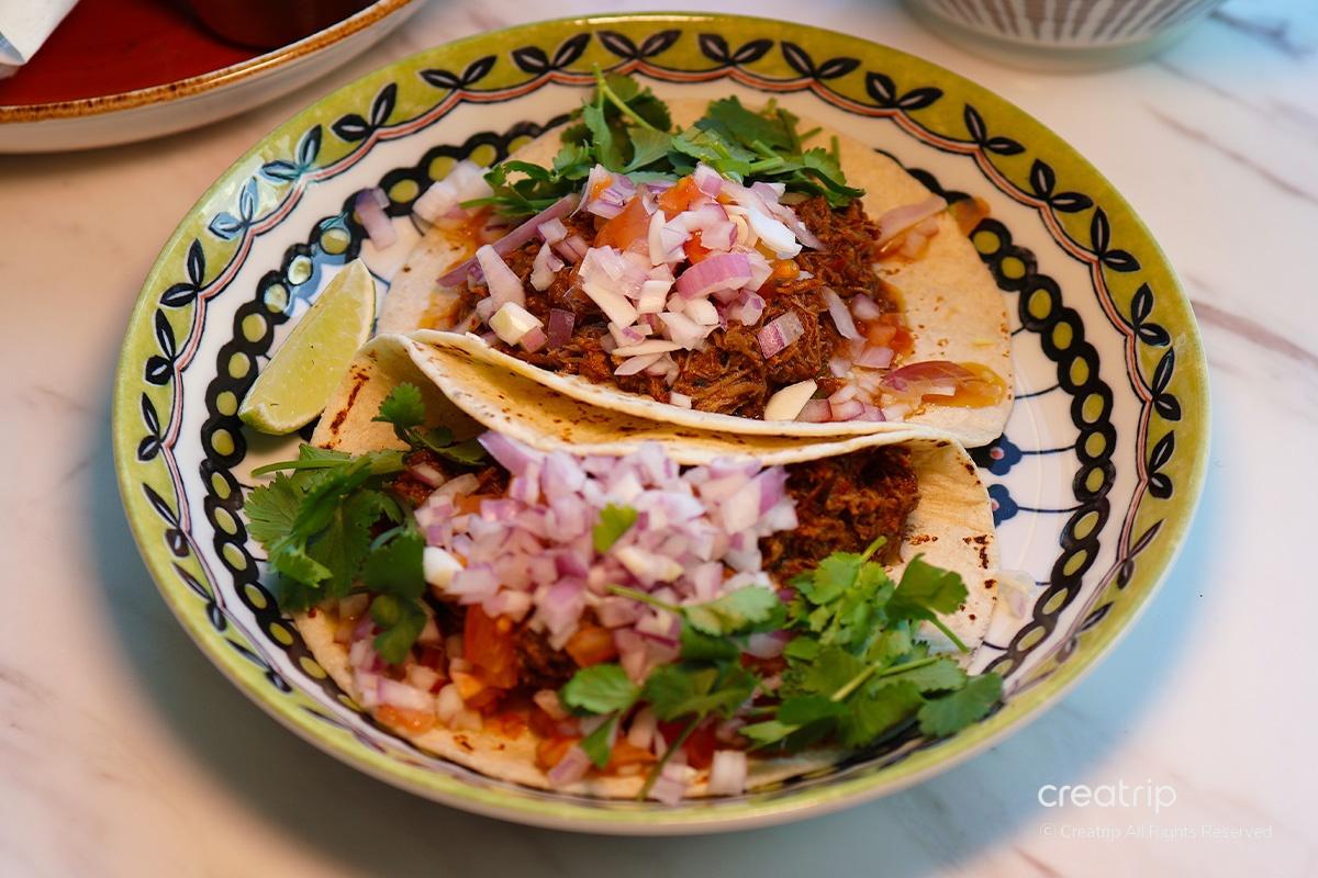 bistro MEXI的塔可，色泽浓郁，配有新鲜香菜和洋葱，呈现正宗墨西哥风味。