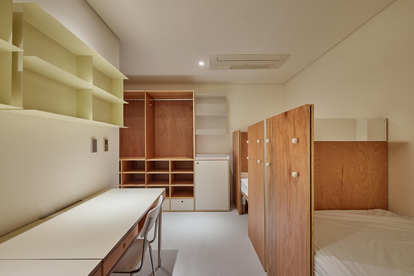 ภายในห้องพักใน Co-living House Mangrove Sinseol ที่มีการออกแบบเป็นเจ้าของร่วมกัน ตกแต่งด้วยเฟอร์นิเจอร์ไม้และมีที่เก็บของมากมาย