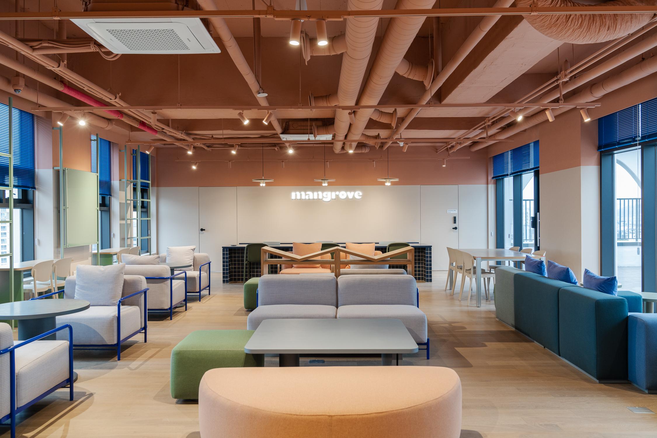 ห้องนั่งเล่นใน Co-living House Mangrove Sinchon เฟอร์นิเจอร์ที่จัดไว้อย่างมีสไตล์และพื้นที่เพดานสูง มีชื่อ Mangrove ติดอยู่บนผนัง