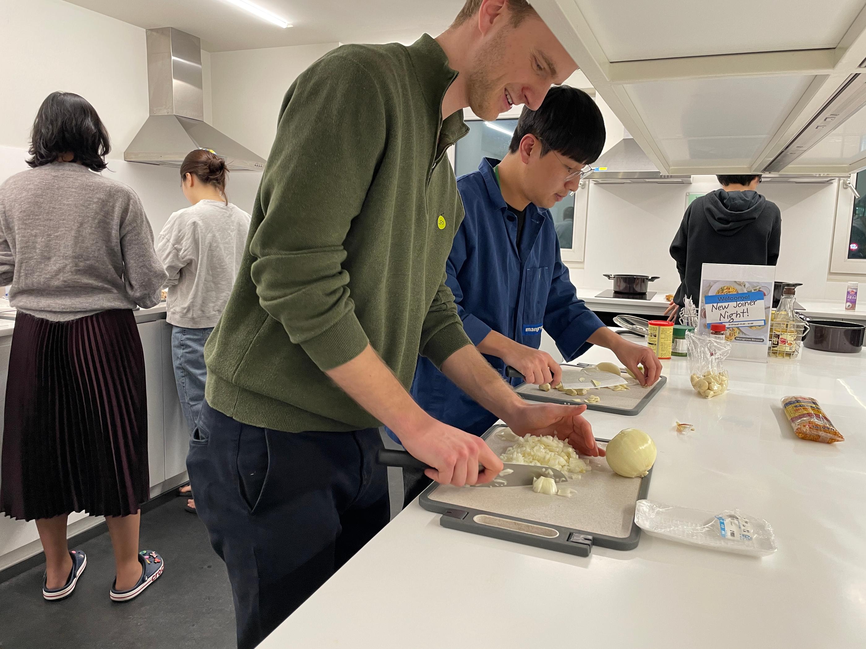 กลุ่มคนที่ร่วมกันทำกิจกรรมทำอาหารใน Co-living House Mangrove โดยมีส่วนร่วมในการเตรียมวัตถุดิบอย่างสนุกสนาน