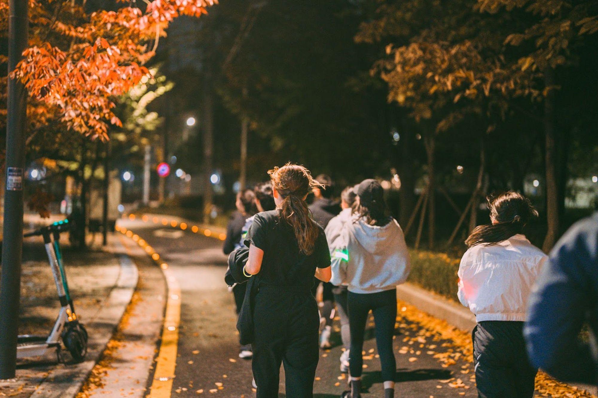 ภาพของกลุ่มคนที่กำลังวิ่งกลางคืนในใจกลางเมืองที่มีไฟสว่างเป็นแนวทาง สร้างกิจกรรมออกกำลังกายกลางแจ้งร่วมกัน