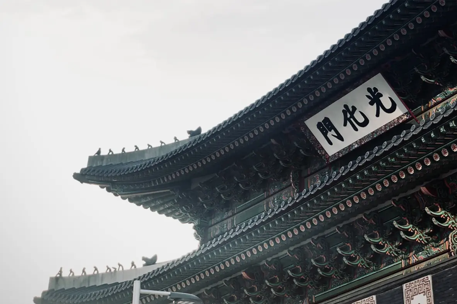 首爾光化門，傳統韓國建築的屋頂特寫，突出其精緻的裝飾與現代背景的對比。