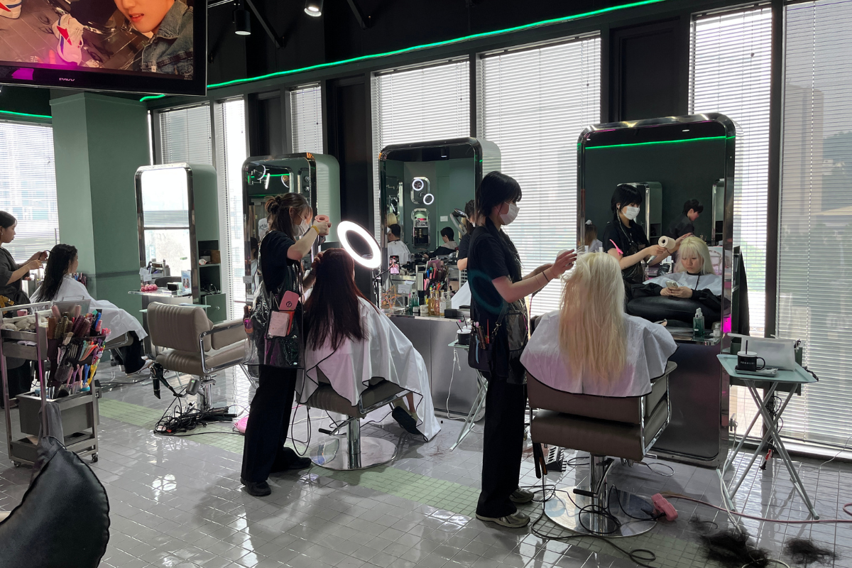 Interno di un moderno salone di bellezza coreano con parrucchieri che lavorano su clienti, offerta di servizio professionale.