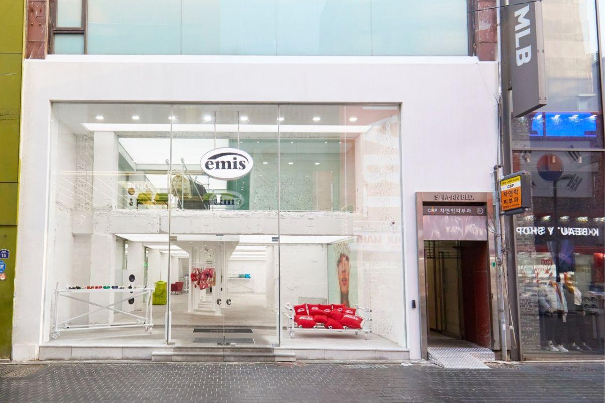位於首爾明洞的emis品牌旗艦店外觀，展示簡潔的現代設計和明亮的玻璃入口，方便顧客進出。