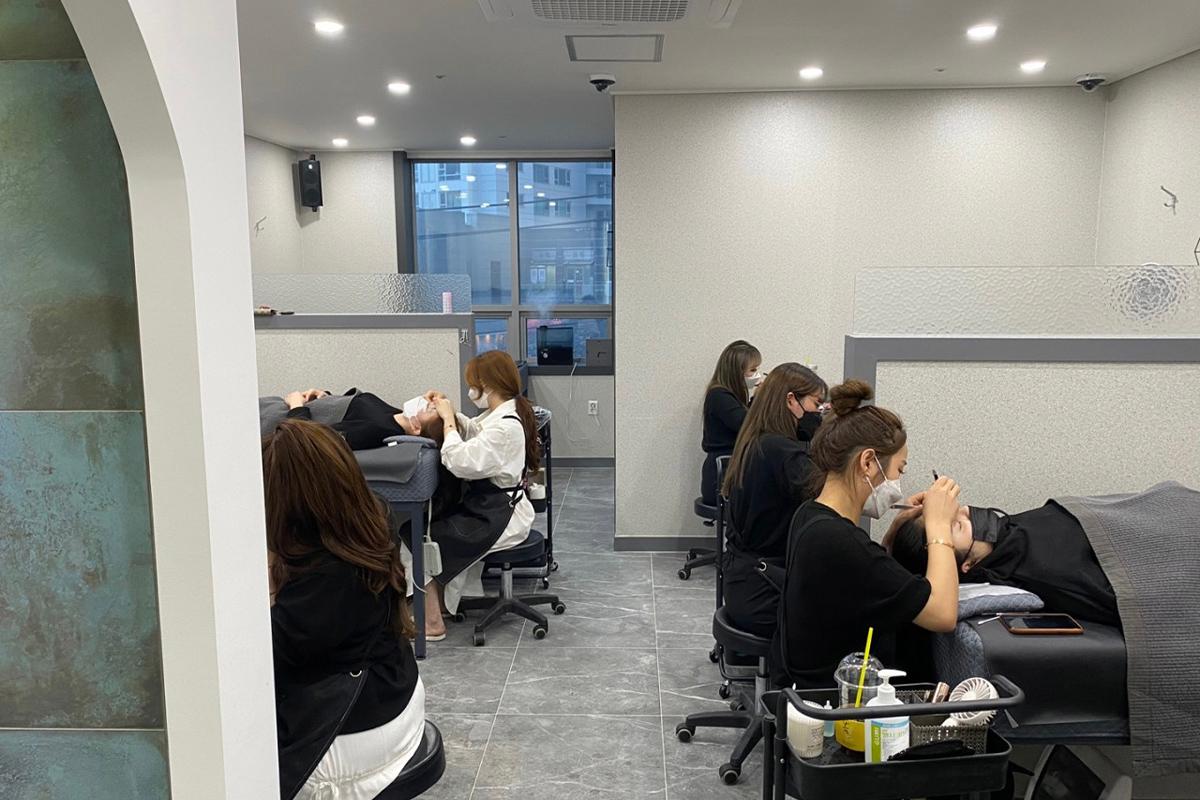 KoResQ beauty academy students practicing eyelash extension techniques in a modern training room.