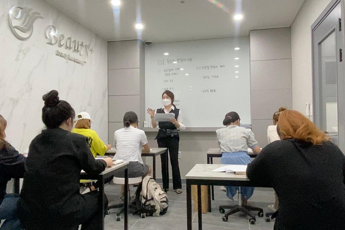 KoResQ beauty academy lecture session with students attentively taking notes from the instructor.