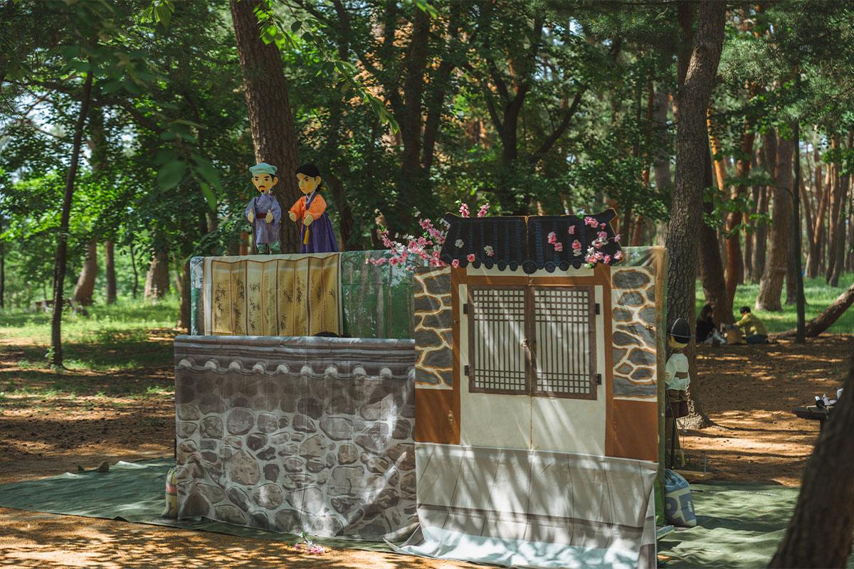 Traditional puppet show in a forest setting at Heo Gyun Heo Nanseolheon Memorial Hall, Korea.