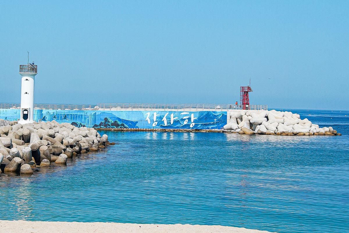 Jangsa Port's vibrant blue sea with lighthouse and breakwater, Sokcho, Korea.
