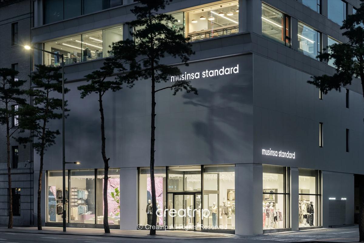 明洞Musinsa Standard外觀夜景，落地窗展示服飾與櫥窗佈置，適合安排9月明洞購物與折扣活動行程的街景照。