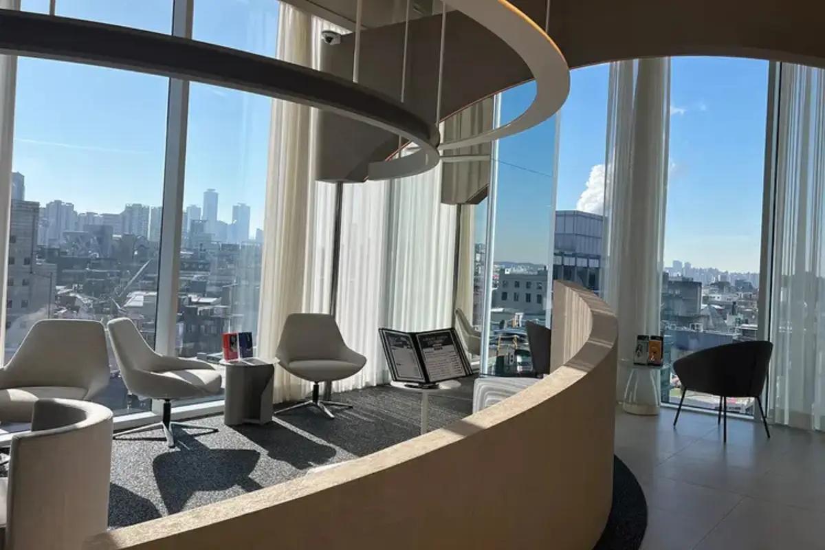 A spacious waiting area at Forena Clinic with large windows offering city views and comfortable seating.