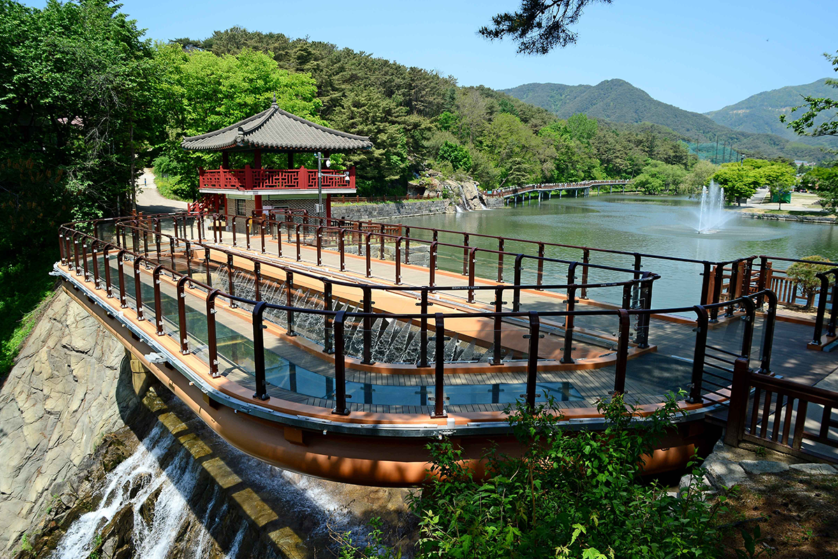 Yongchu Waterfall's glass observation deck over Uirimji Reservoir with lush forest views in Jecheon, South Korea
