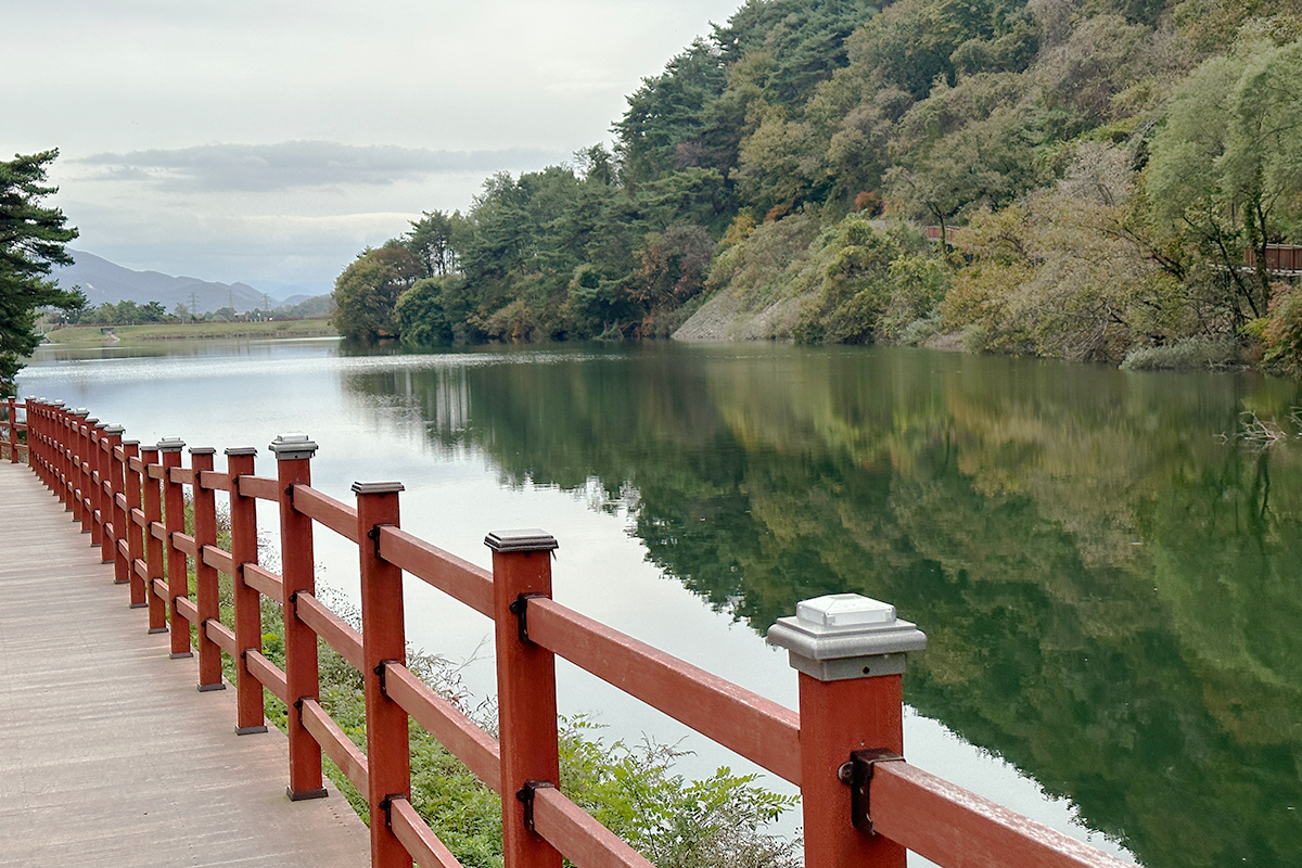 A scenic walking path along Biryongdam Reservoir with reflections in the water, Jecheon