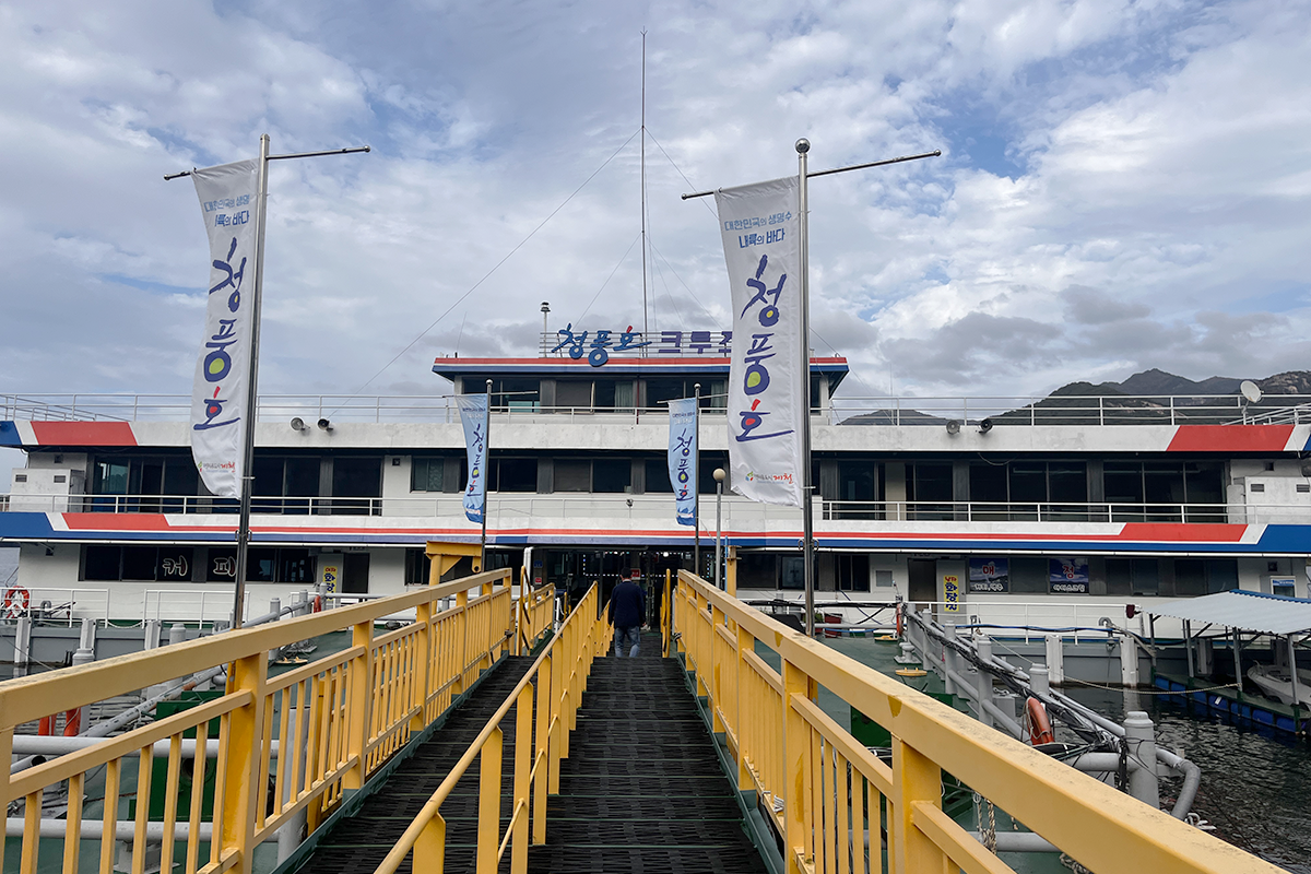 Entrance to the Choongju Lake Cruise at Cheongpung with flags fluttering under a blue sky in Jecheon