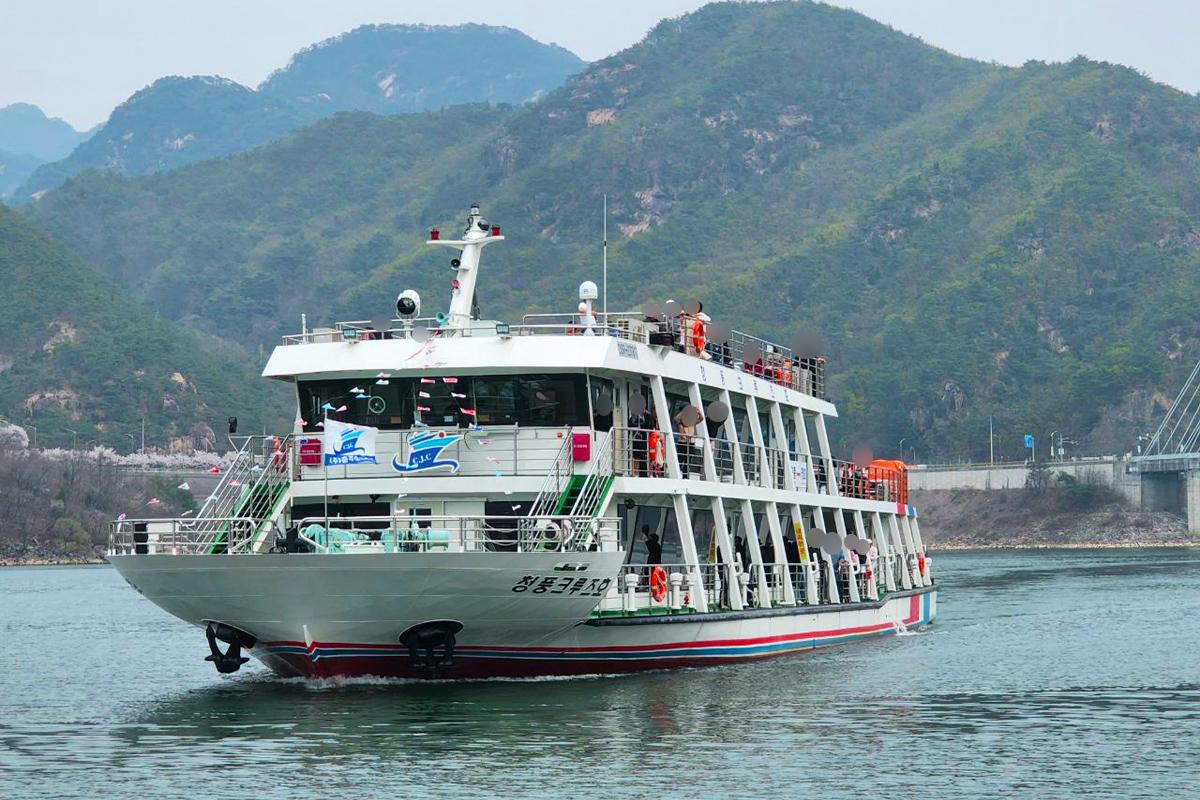 Cruise ship navigating through Cheongpung Lake surrounded by picturesque mountainous scenery in Jecheon