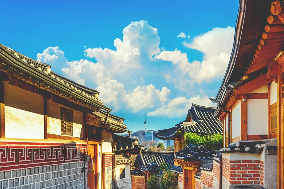 首爾北村韓屋村的全景，天空湛藍，韓屋的屋頂和南山塔清晰可見