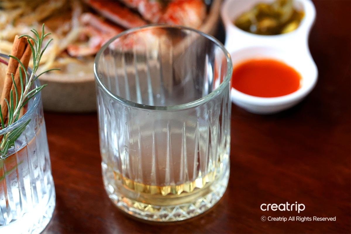 Refreshing apple highball with dried apple garnish, pouring on ice at Earl bar.