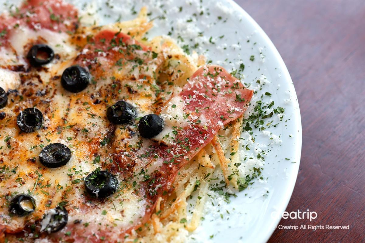 Close-up detail of bacon cheese potato pancake at Earl, dusted with herbs and spices.