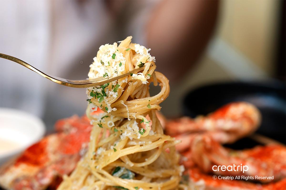 A twirl of cheesy pasta at Earl, topped with fresh herbs, paired with seafood.