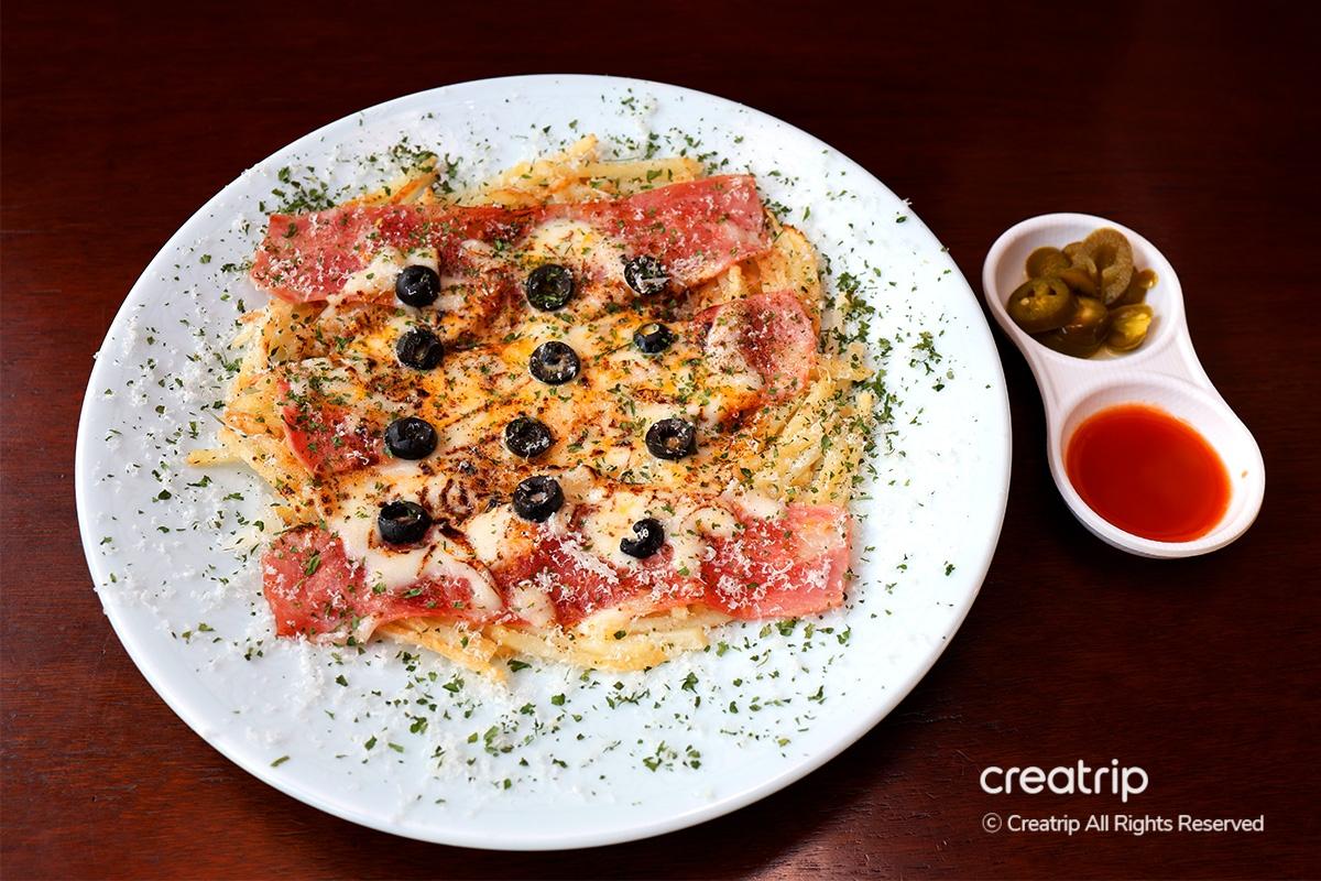 Top view of Earl's bacon cheese potato pancake garnished with olives and herbs.