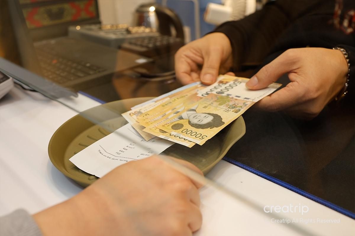 Scambio di grandi note di won coreani attraverso il vassoio presso il Mega Currency Exchange in Jongno-gu, Seoul.