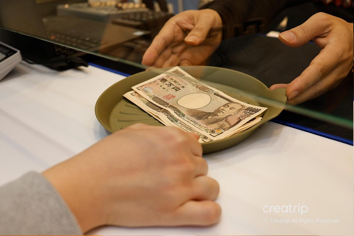 Cliente consegna Yen giapponesi al personale del Mega Currency Exchange per lo scambio con won coreani.