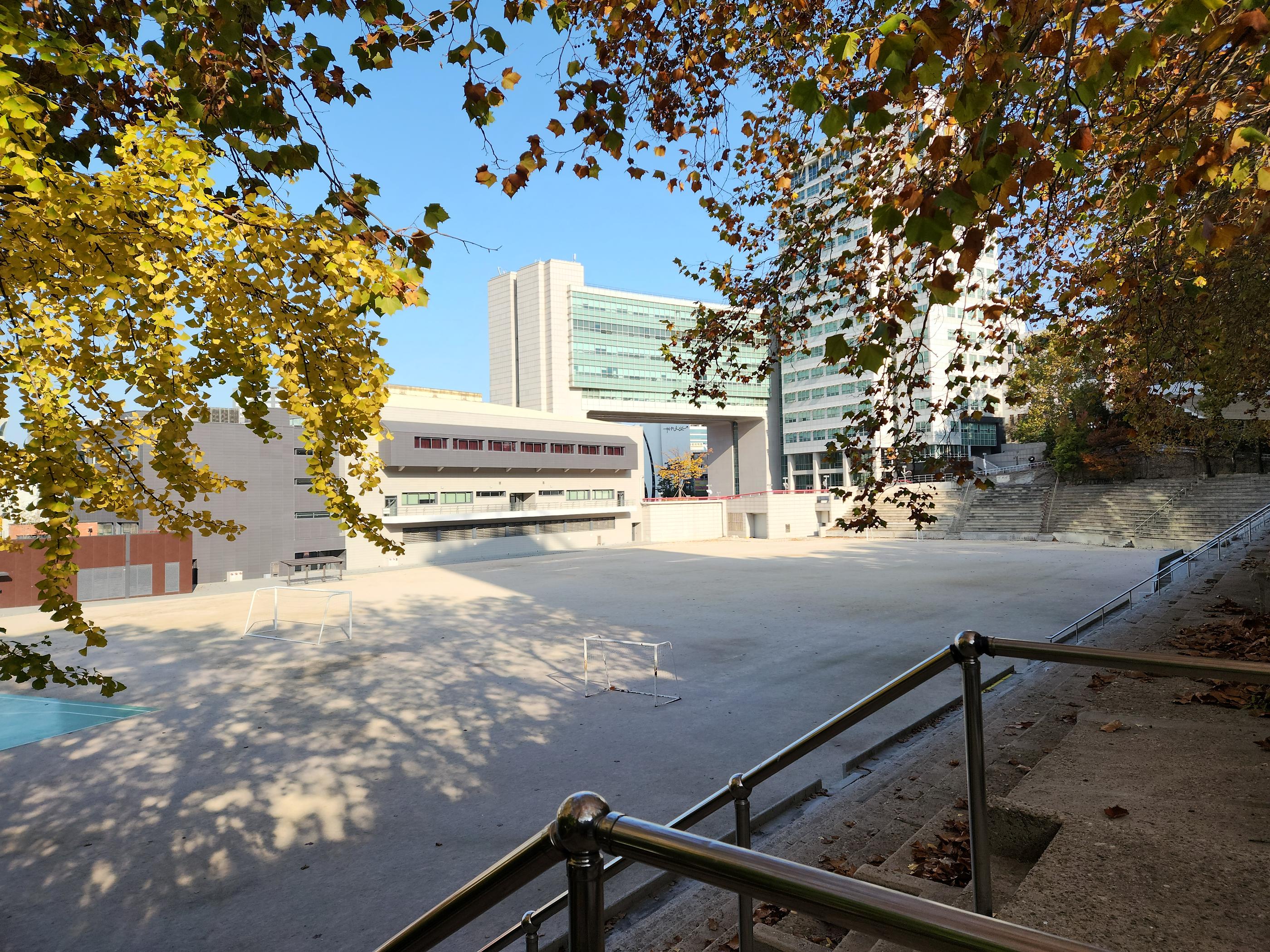 三位外国学生在弘益大学校园合影，他们通过访谈分享在弘大语学堂学习韩文的经验。